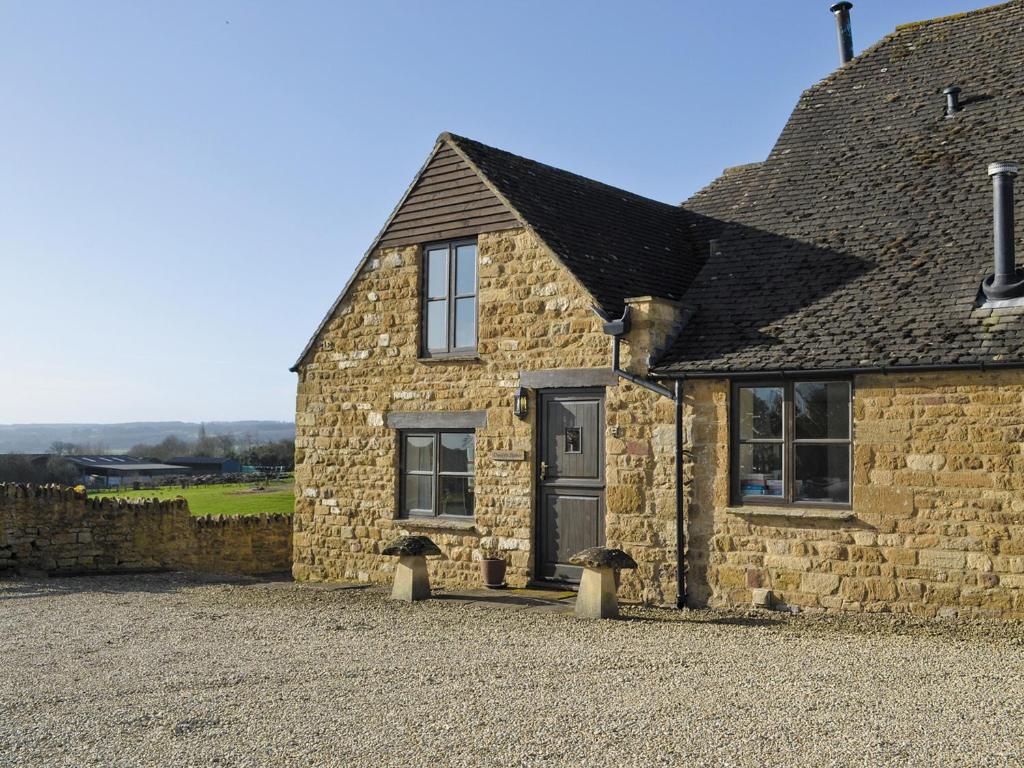 une maison en pierre avec une porte et des fenêtres noires dans l'établissement Dustys Stable - E4751, à Ebrington