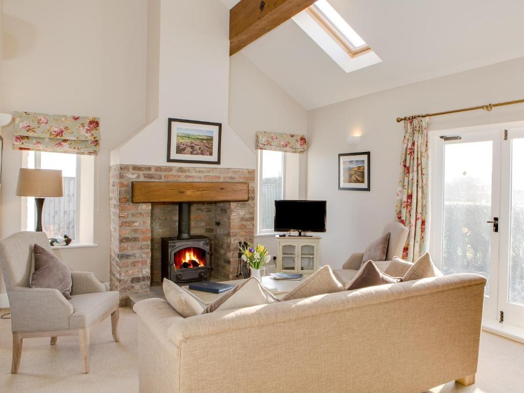 ein Wohnzimmer mit einem Sofa und einem Kamin in der Unterkunft Lodge Cottage in Scalby