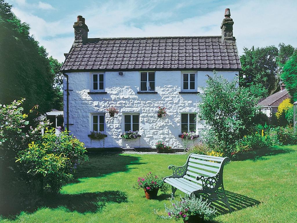 a white house with a bench in front of it at Foxes Reach in Trelleck