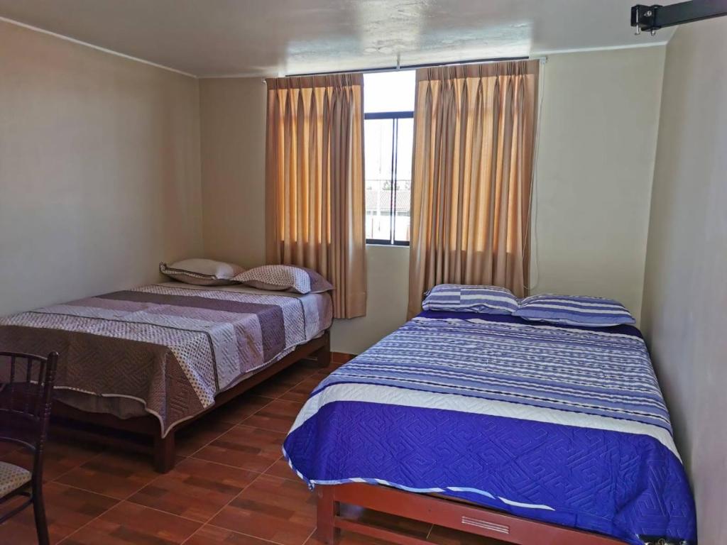 1 dormitorio con 2 camas y ventana en Catalina Huanca Resort, en San Jerónimo