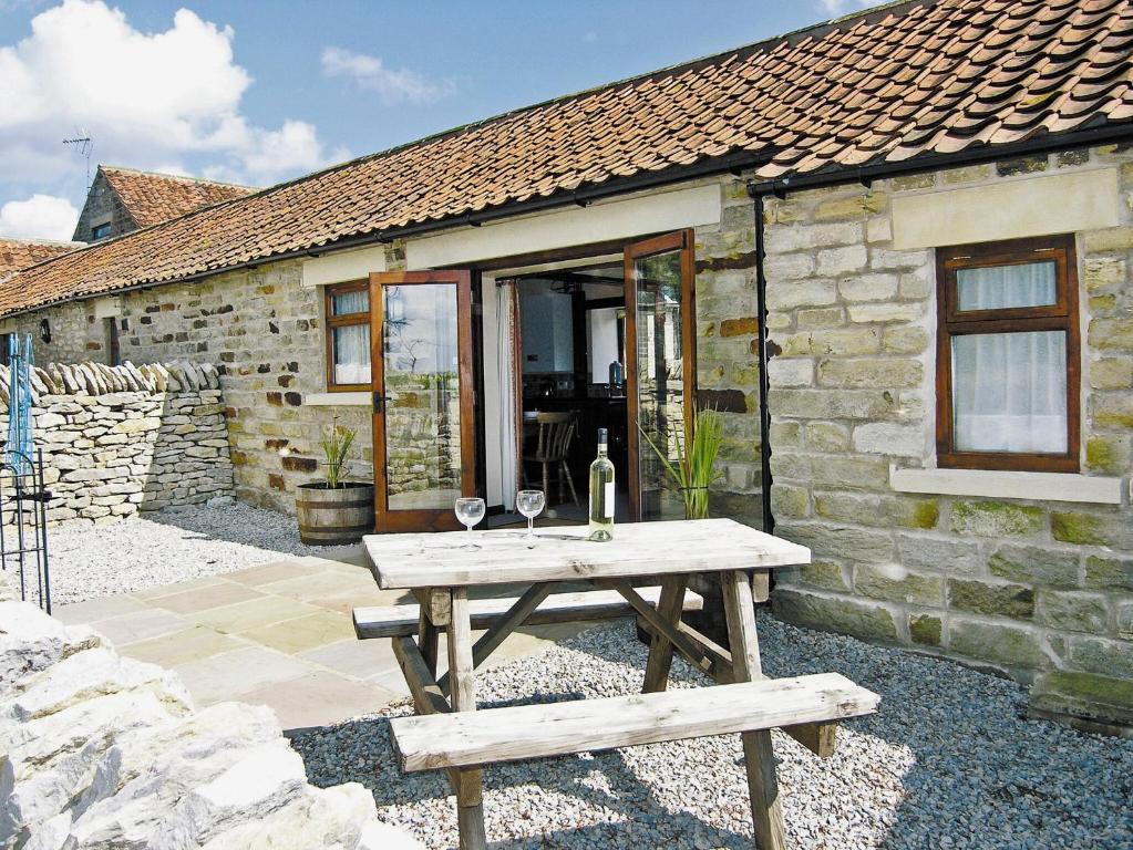 a wooden picnic table in front of a stone cottage at Pear Tree Cottage in Gillamoor