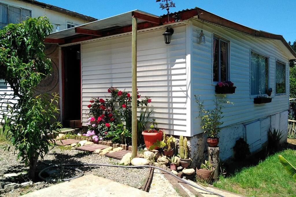une petite maison blanche avec des fleurs devant elle dans l'établissement Cabaña romantica ideal para ir en pareja, à Valparaíso