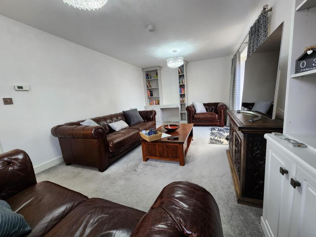 sala de estar con sofás de cuero y mesa en Spacious 3-bed Luxury Maidstone Kent Home - Wi-Fi & Parking en Kent