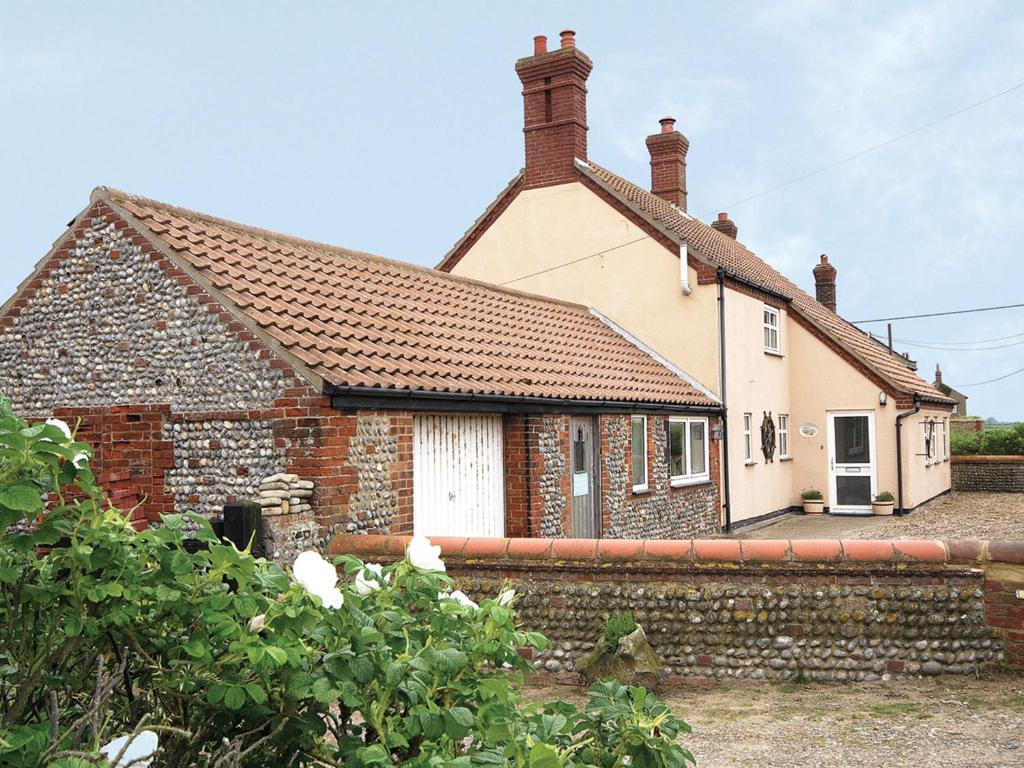 una pequeña casa de ladrillo con una pared de piedra en Seafarers en Lessingham