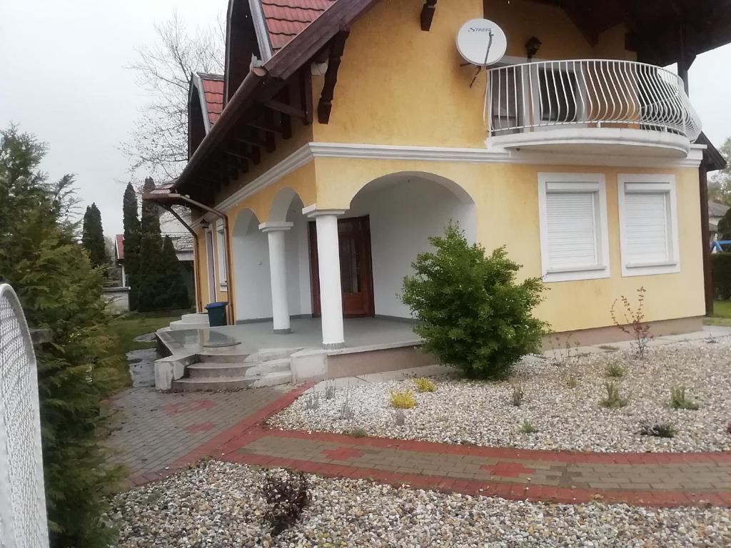 Une petite maison jaune avec une horloge. dans l'établissement Vitorlás villa földszint, à Balatonlelle