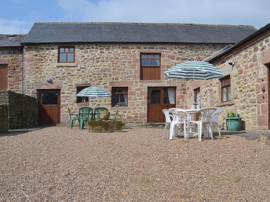 a patio with chairs and umbrellas in front of a building at Barn Owl Cottage in Cromford