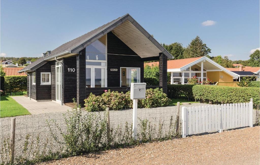 a black house with a fence in front of it at Two-Bedroom Holiday Home In Bjert in Binderup Strand