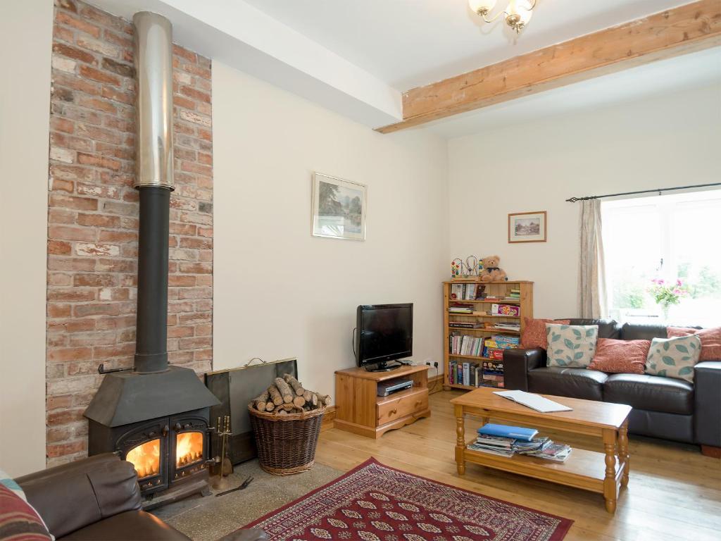 a living room with a brick wall and a fireplace at The Stable in Foxham