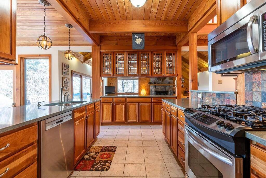 cocina con armarios de madera y horno con fogones en 4BR / 3BA Smart Home w/ Hot Tub, Mountain View Ski, en Stratton Valley