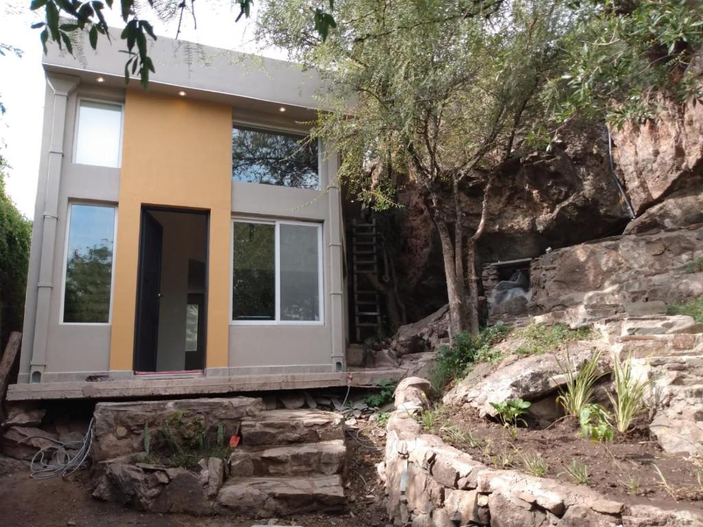 a house built into a cliff with a stone wall at Koba, una experiencia memorable in Potrero de los Funes