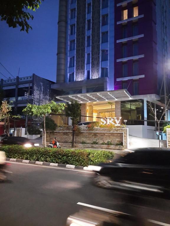 泗水Surabaya River View Hotel的一辆汽车在建筑物前的街道上行驶