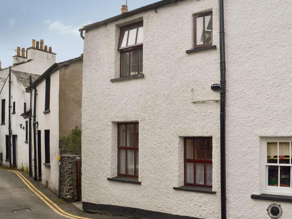 a white building with red windows on a street at Begbie Cottage in Bowness-on-Windermere