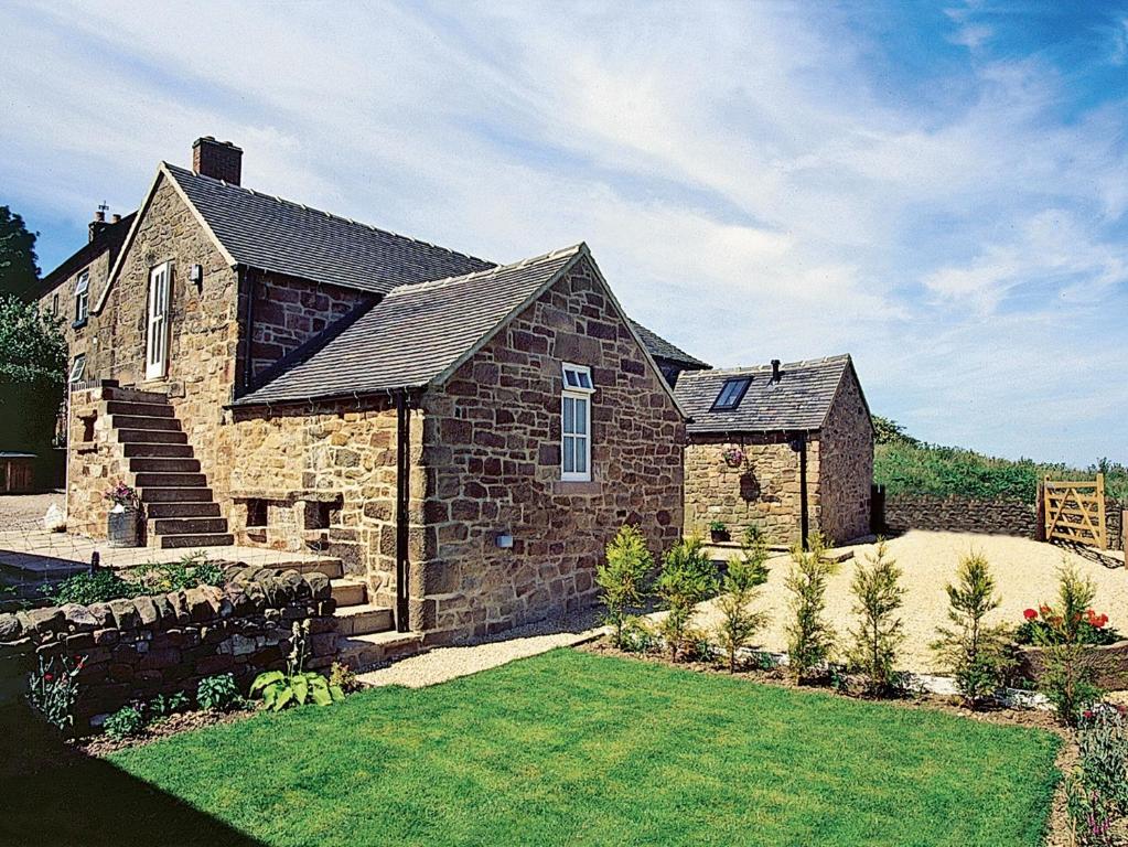 a large stone house with a grass yard at Spring Cottage-e3846 in Kirk Ireton