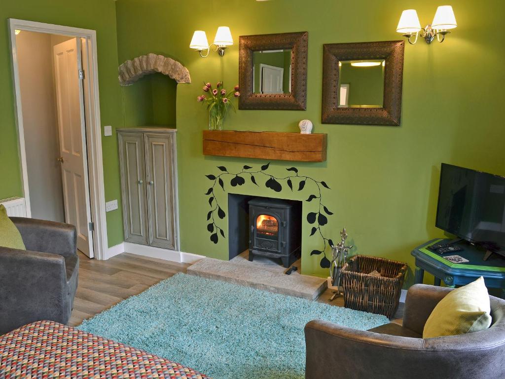 a living room with a fireplace and green walls at Nutmeg Cottage in Tideswell