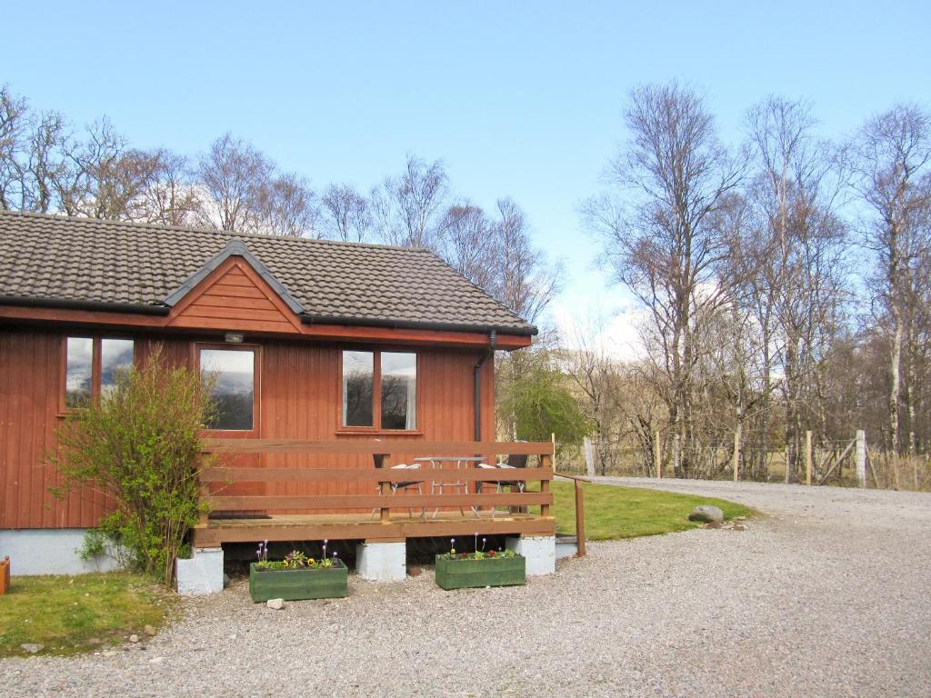 una cabaña de madera con un banco delante en Birch Lodge - 28880, en Torcastle