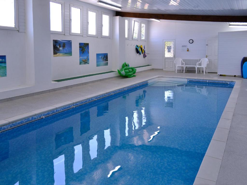 a large swimming pool with blue water in a building at Little Content Farm Cottage in Cury