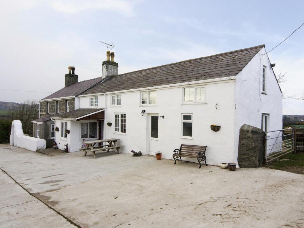 a white house with a bench and a table at Deuglawdd Cottage - Hw7788 in Aberdaron