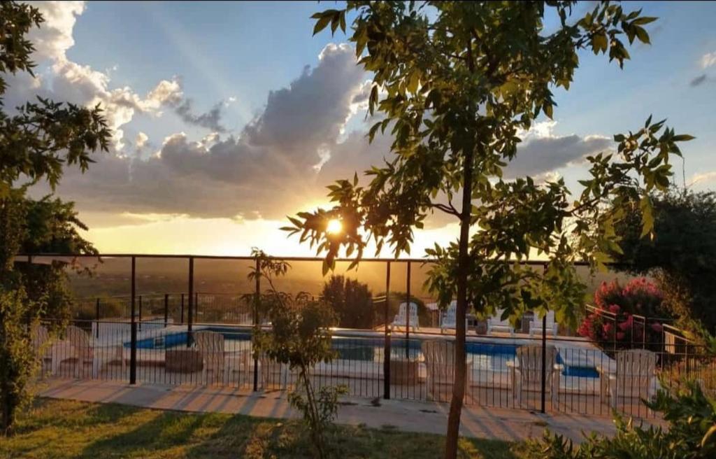 a view of a swimming pool with the sun setting at Aiken Cabañas in Villa Cura Brochero