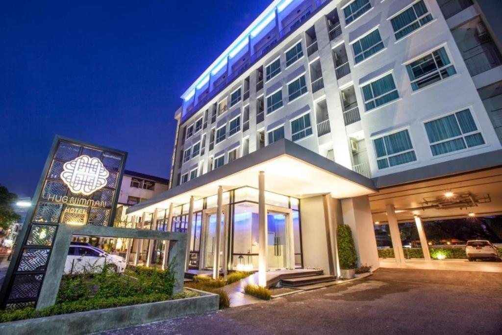 a large white building with a sign in front of it at Hug Nimman Hotel in Chiang Mai