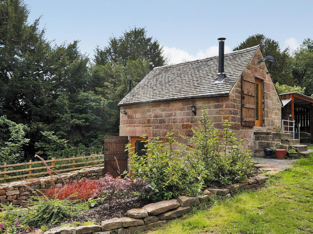 Highpeak Junction的住宿－Cornstore Cottage，一座古老的石头房子,前面设有一个花园