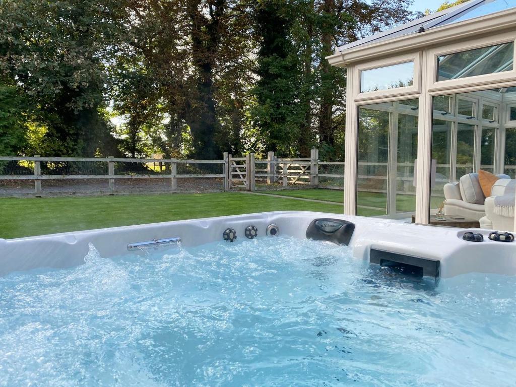 una bañera de hidromasaje en un patio trasero con una casa de cristal en Rectory Cottage, en Blankney