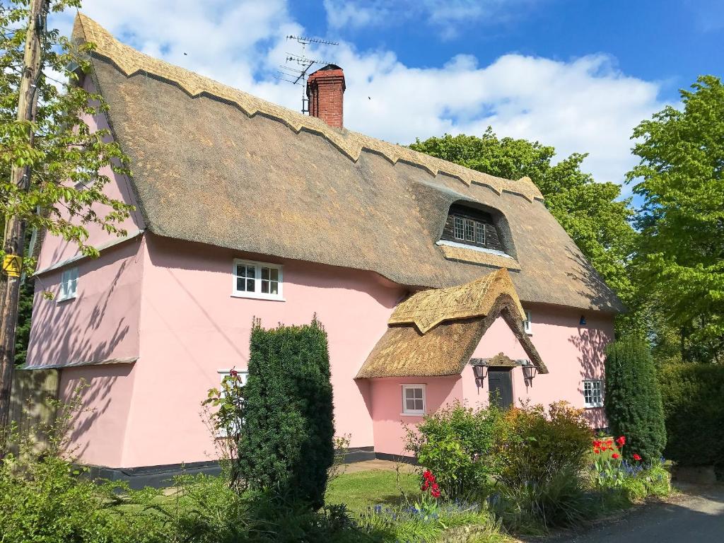 a pink house with a thatched roof at Old High Hall in Cowlinge