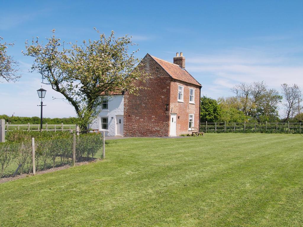 uma antiga casa de tijolos com um grande jardim de relva em Somer Leyton Cottage em Chapel Saint Leonards