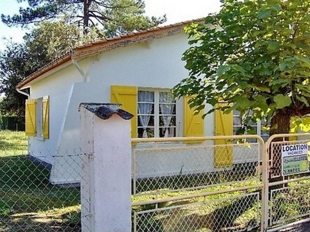 une petite maison avec une fenêtre jaune et une clôture dans l'établissement Maison près de la plage avec parking, jardin clos, et équipements complets 6 couchages - FR-1-246A-167, à Saint-Trojan-les-Bains