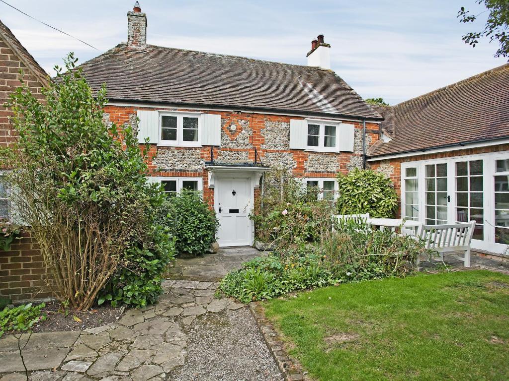 a brick house with a white door and a yard at Apple Tree Cottage in West Wittering