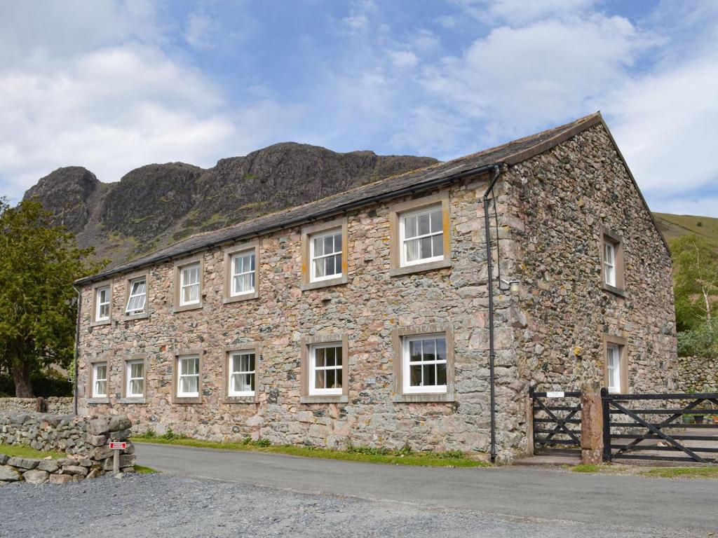 an old stone building with a mountain in the background at The Retreat in Nether Wasdale