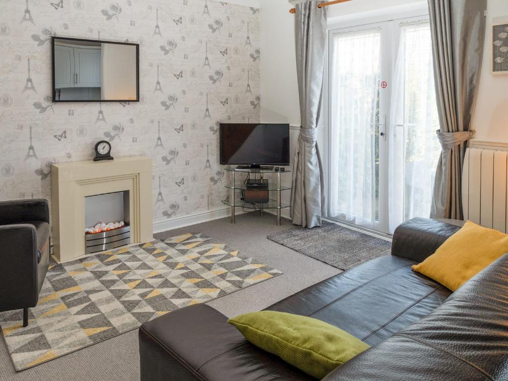 a living room with a couch and a tv at Beach Walk Cottage in Scarborough