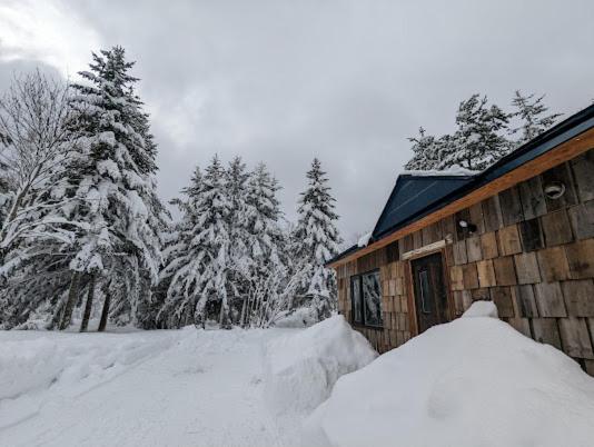 a house with a pile of snow in front of it at 暮らす宿ソラプチ Sorapchi Cabin 