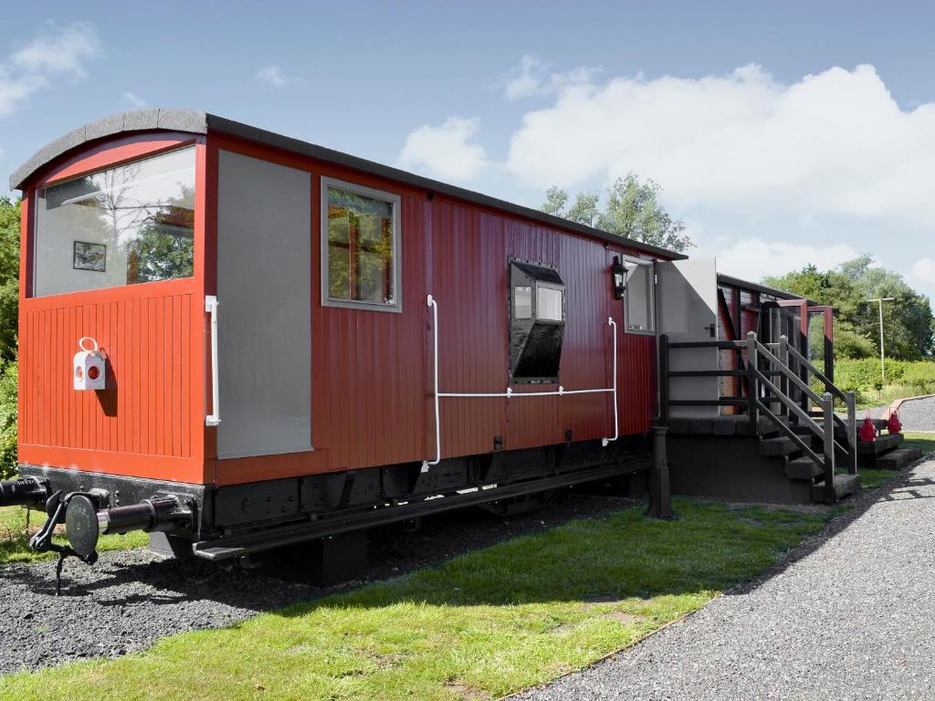 a red train car is sitting on the grass at The Guards Van in Wetheringsett