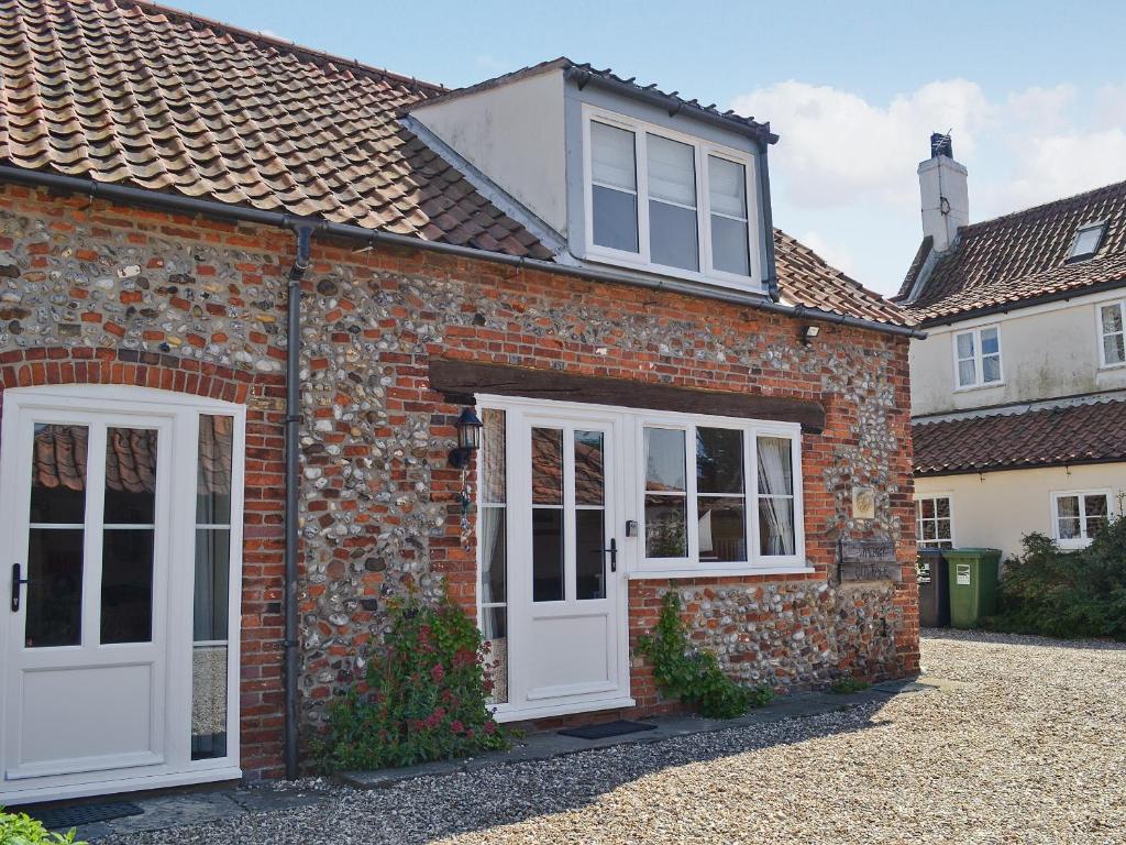 uma casa de tijolos com portas e janelas brancas em Wherry Cottage em Wells next the Sea