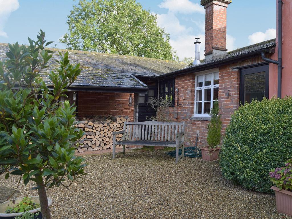 a wooden bench in front of a brick house at The Gig House in Stonham Aspall