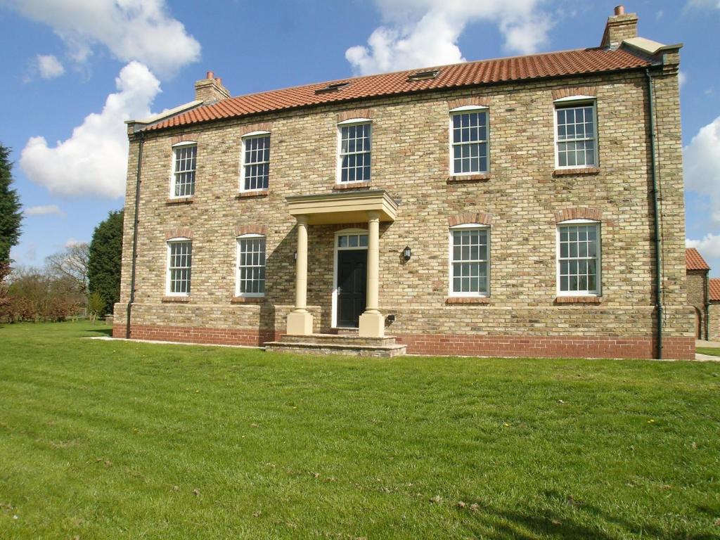 an old brick house on a grassy field at Rascal Wood in Holme upon Spalding Moor