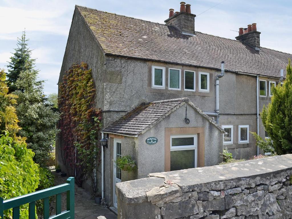 an old stone house with a stone wall at Tree Tops in Youlgreave