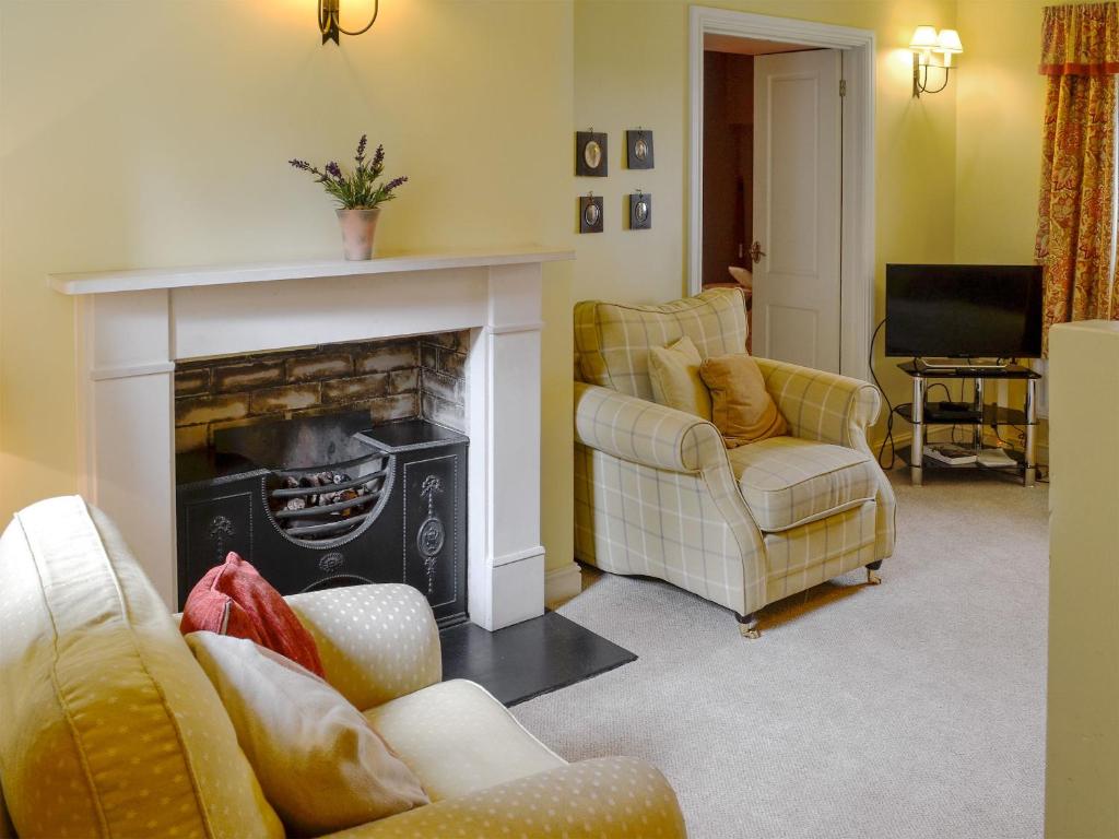 a living room with a fireplace and two chairs at The Old Stables in Uldale