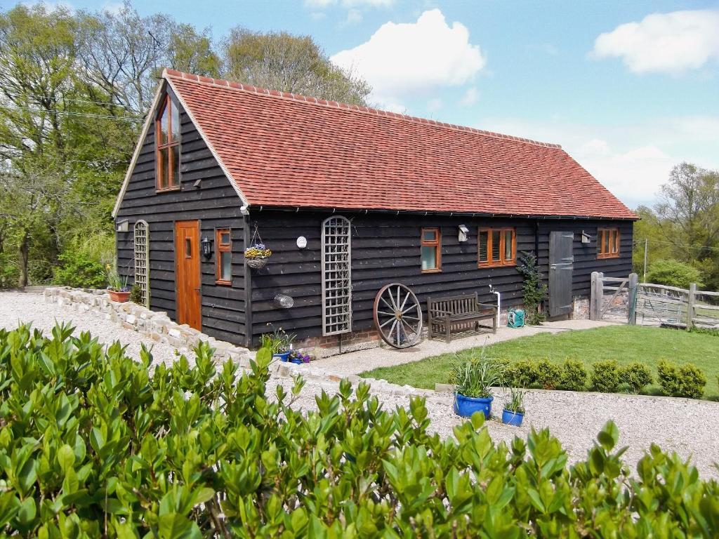 a black barn with a red roof at Swallows Barn in Dallington