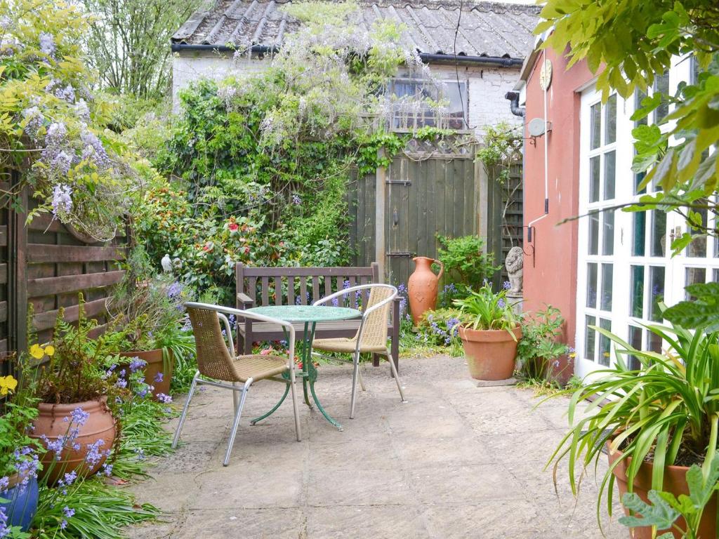 a patio with a table and chairs in a garden at Wisteria Cottage in Aylsham