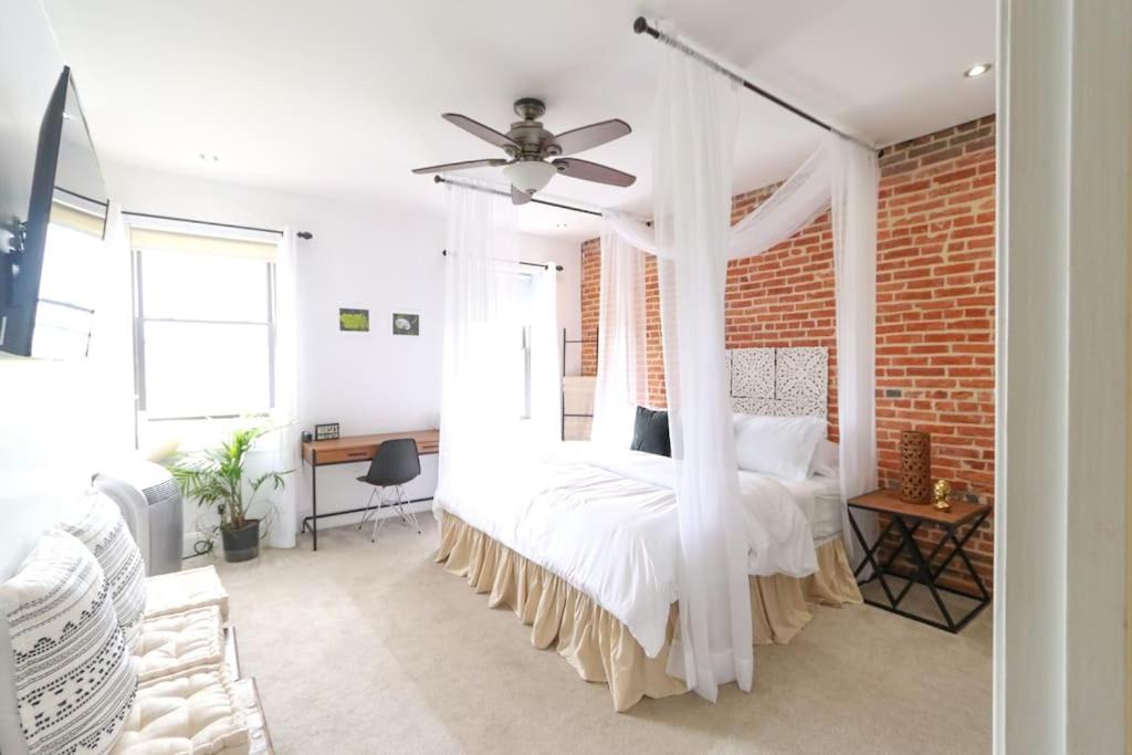 a bedroom with a white bed with a ceiling fan at The Hidden Paradise Home Studio, Downtown City Views, Productions, Families & Large Groups in Baltimore