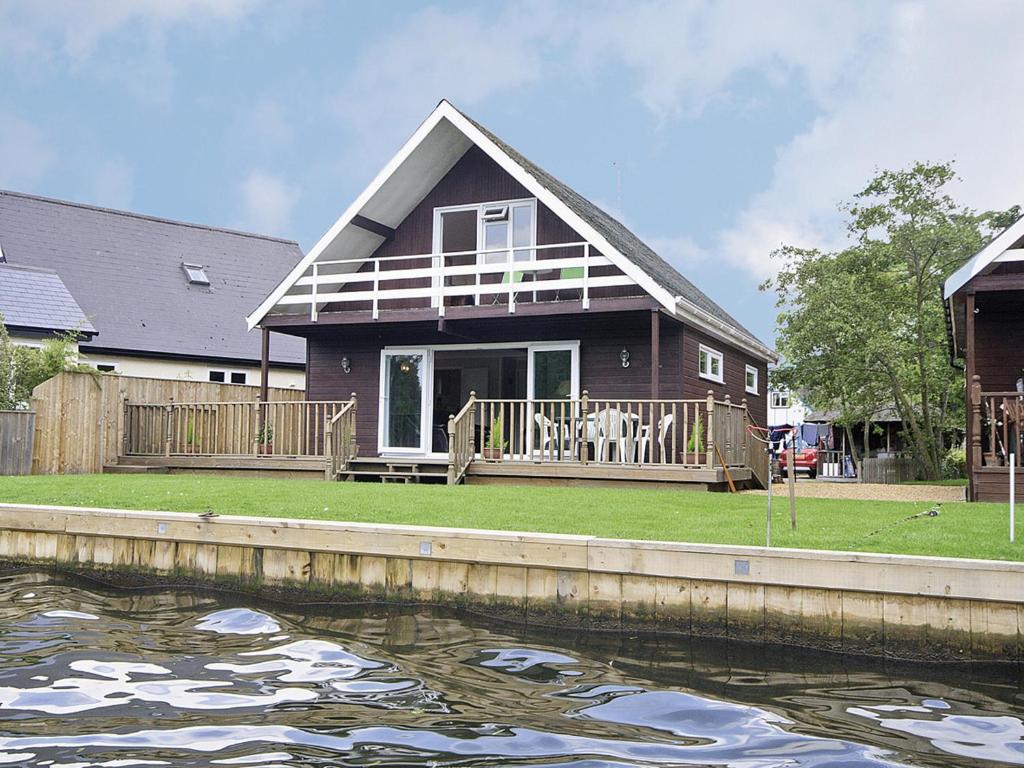 a house with a large deck and a body of water at Watersedge - E1106 in Horning