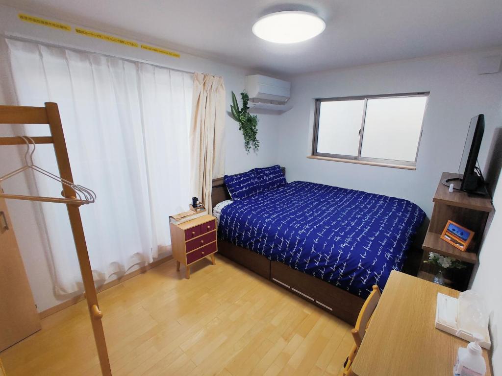 1 dormitorio con 1 cama con edredón azul en K.House, en Tokio