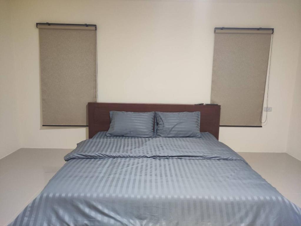 ein Bett mit zwei Kissen in einem Zimmer mit zwei Fenstern in der Unterkunft Home Boss 