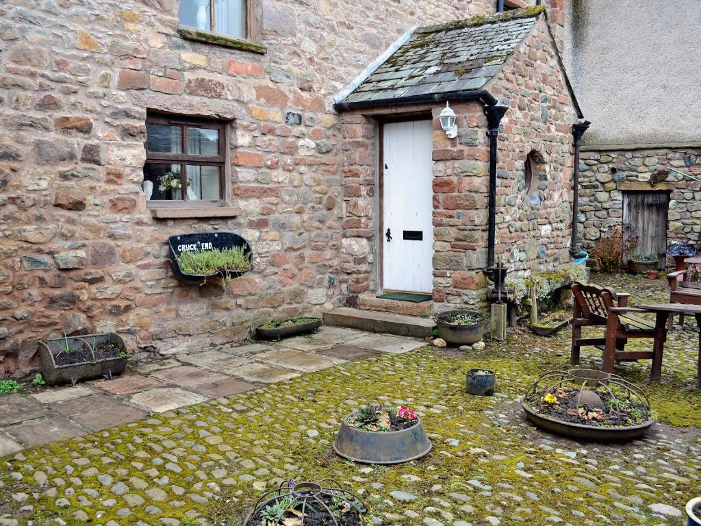 a stone house with a table and a white door at Cruck End - E3749 in Crackenthorpe