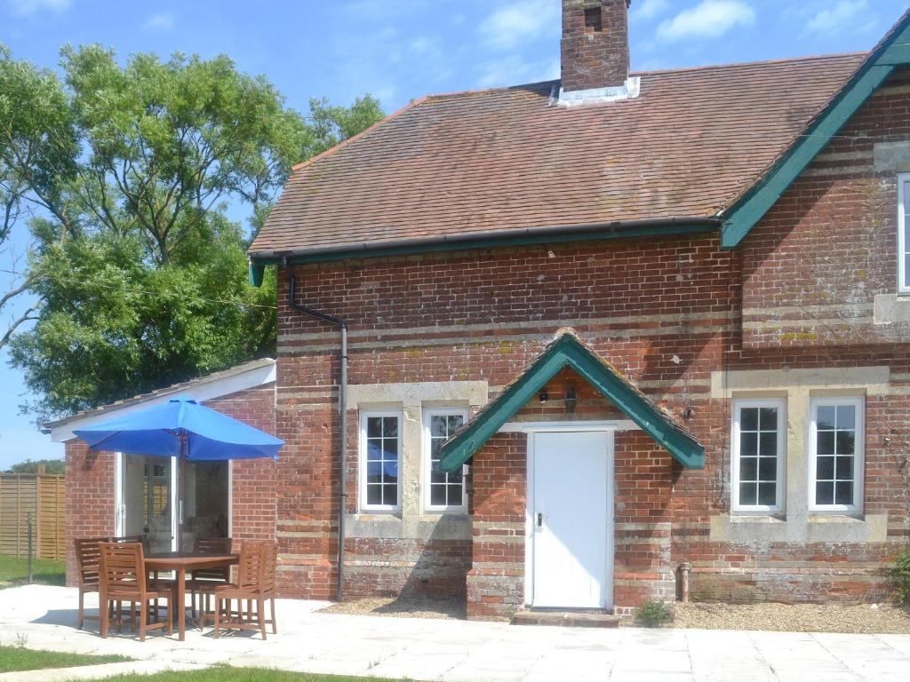 a brick house with a table and an umbrella at Paddock Cottage in Orford