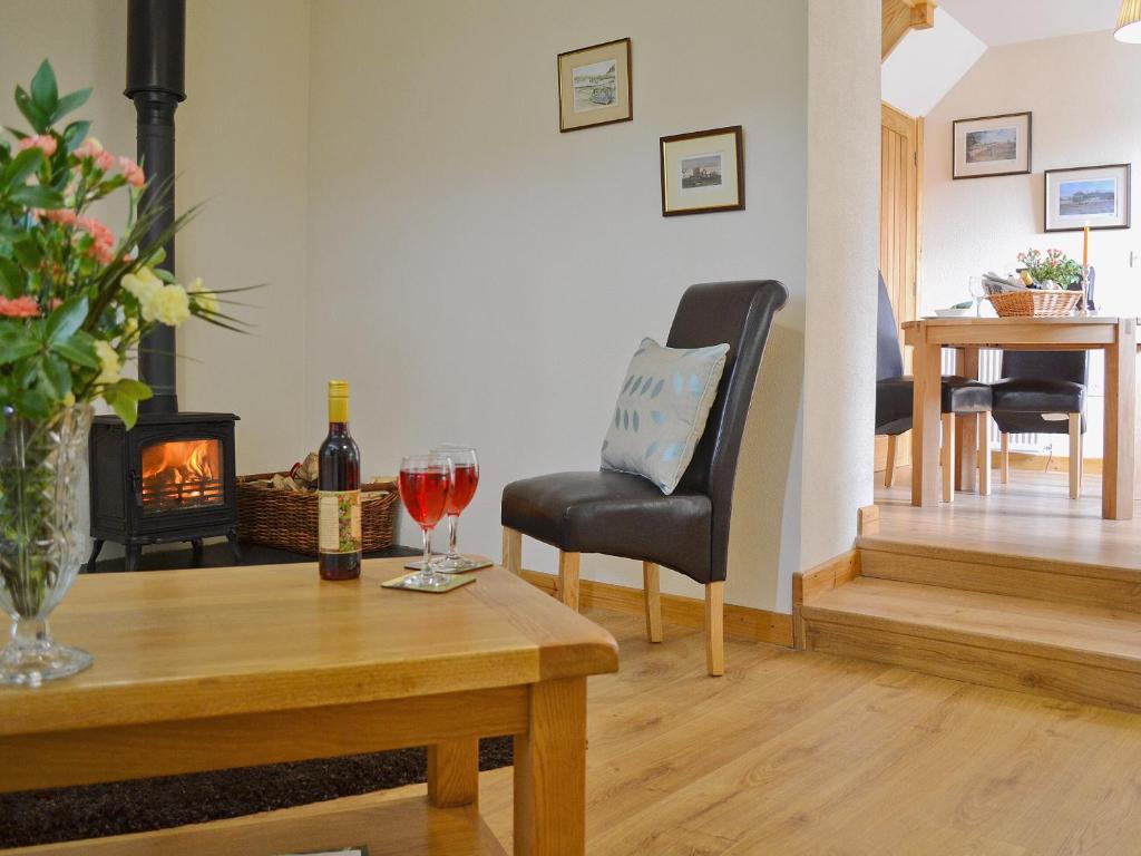 a living room with a fireplace and a table with a glass of wine at Shepherds Lodge in Lamphey