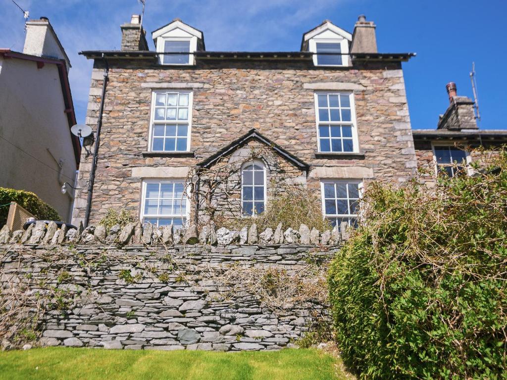 an old stone house with windows and a stone wall at Ellerview House in Ambleside