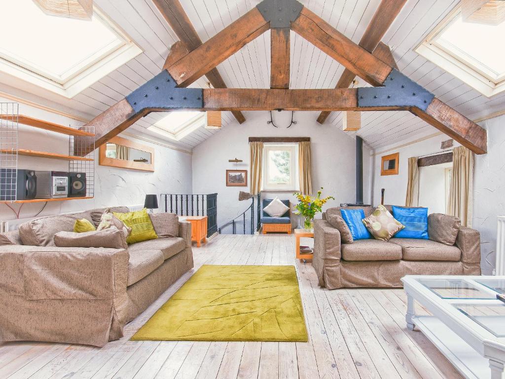 a living room with two couches and a wooden ceiling at Town End Barn in Warslow