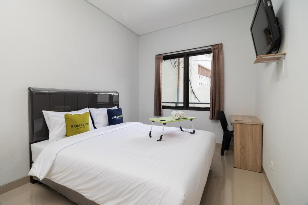 ein Schlafzimmer mit einem großen weißen Bett und einem TV in der Unterkunft Urbanview Hotel Pasar Baru Jakarta by RedDoorz in Jakarta